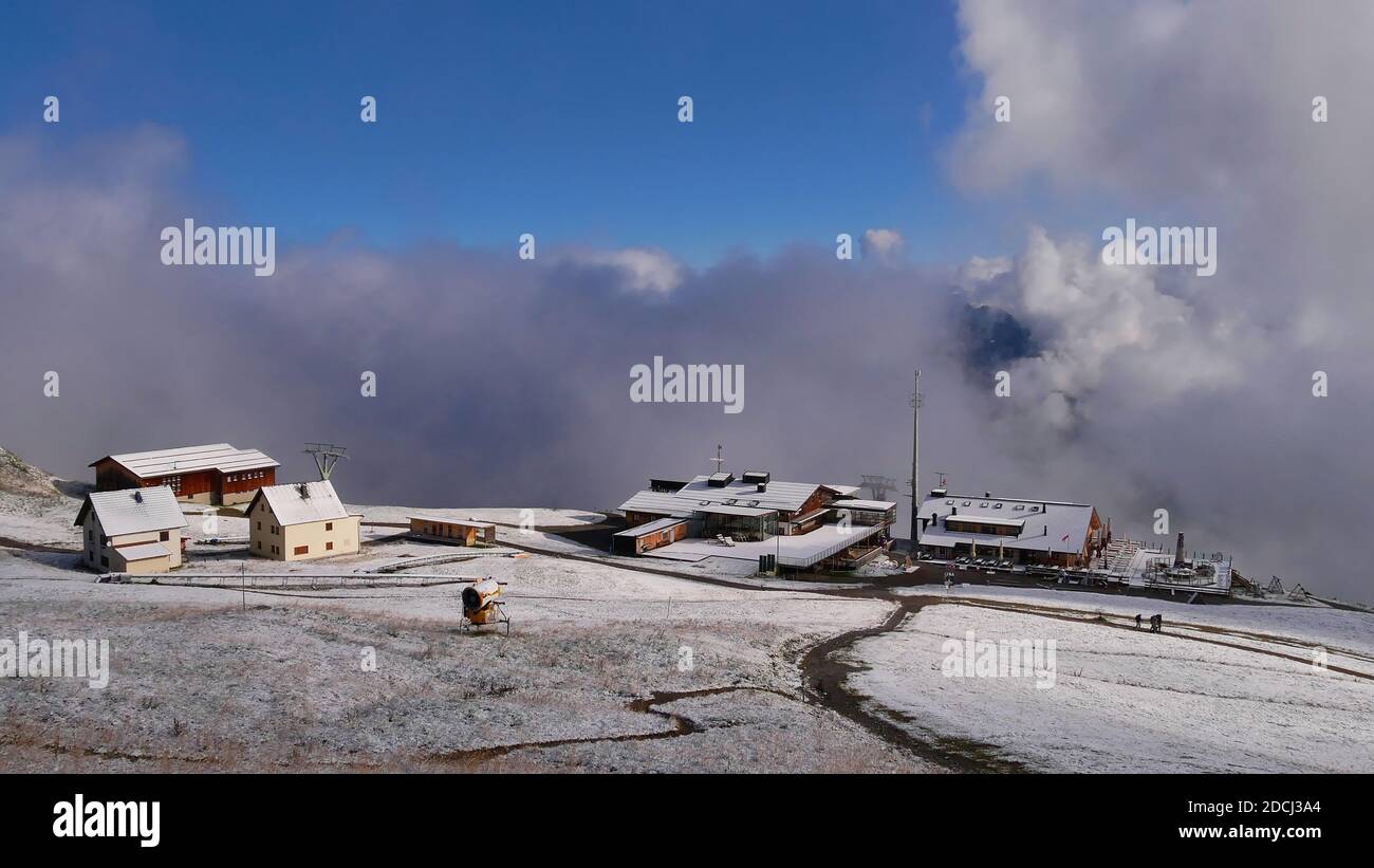 Schöner Panoramablick auf Bergstation einer Seilbahn im Skigebiet in Golm mit schneebedeckten Wiesen, Schneekanonen und aufsteigenden Wolken am sonnigen Tag. Stockfoto