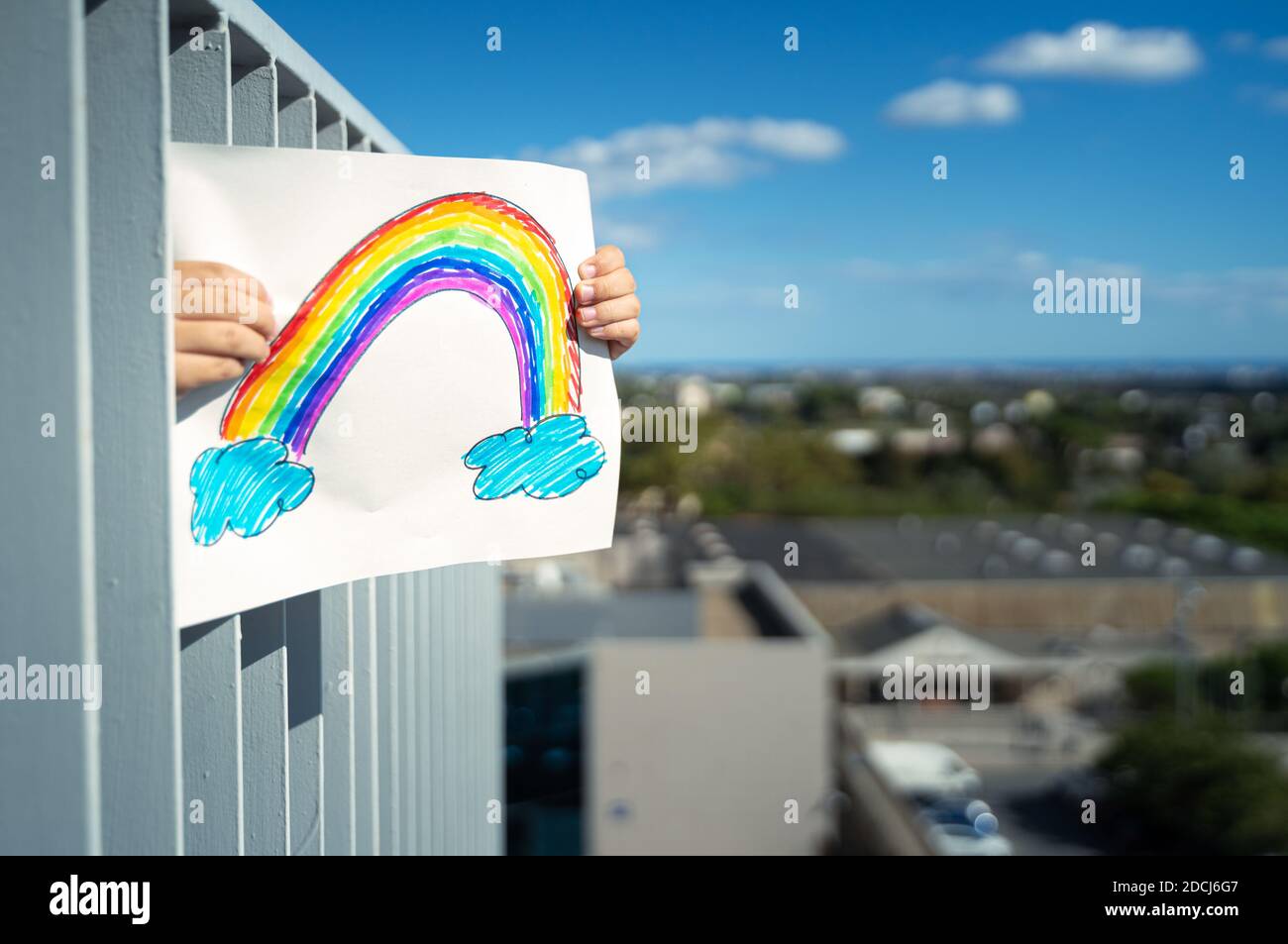 Junge hält diese Regenbogenzeichnung auf dem heimischen Balkon. Coronavirus Quarantänekonzept Stockfoto