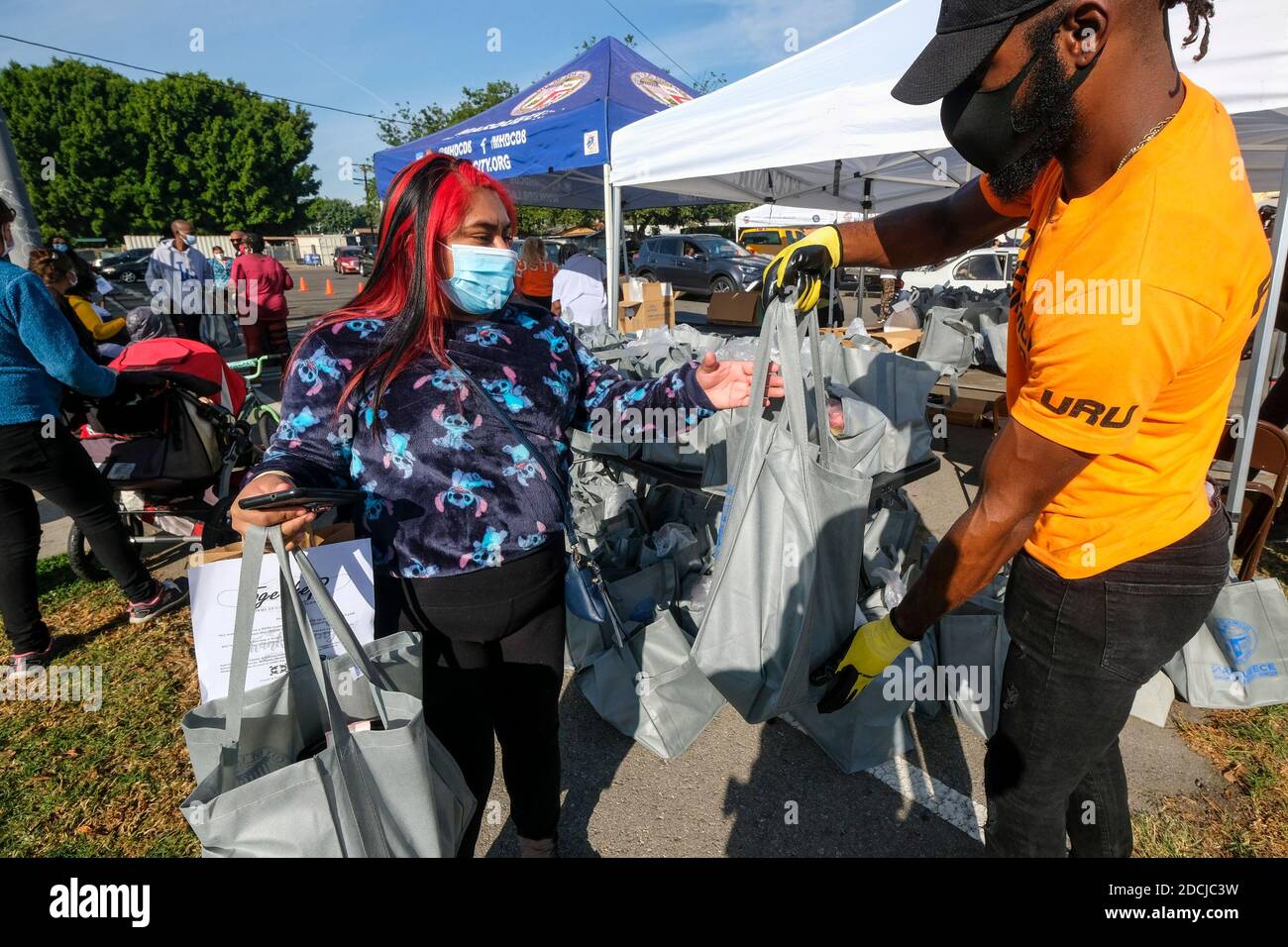 Los Angeles, Kalifornien, USA. November 2020. Ein Freiwilliger übergibt einer Frau während einer Lebensmittelverteilung in Los Angeles am Samstag, den 21. November 2020, eine Tüte mit Lebensmitteln. Die Verteilung bietet Hunderte von kostenlosen, nahrhaften Mahlzeiten to.community Mitglieder in Not, und wird Teil eines größeren Programms, um 6,000 kostenlose Mahlzeiten im November und Dezember für Black Residents, die überproportional von der Coronavirus-Pandemie betroffen sind dienen. Kredit: Ringo Chiu/ZUMA Wire/Alamy Live Nachrichten Stockfoto