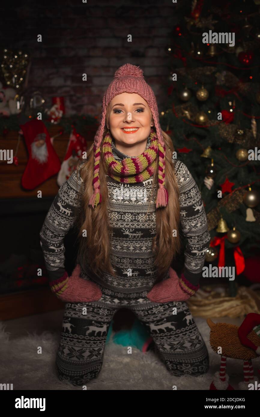 Junge Frau im warmen Anzug mit Hirsch und Strickmütze Mit Fäustlingen lächelnd Stockfoto