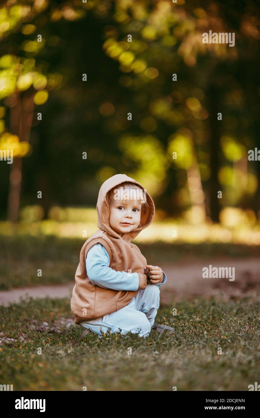 Ein Junge in einer braunen Weste mit Kapuze geht Durch den Herbstwald am Abend Stockfoto