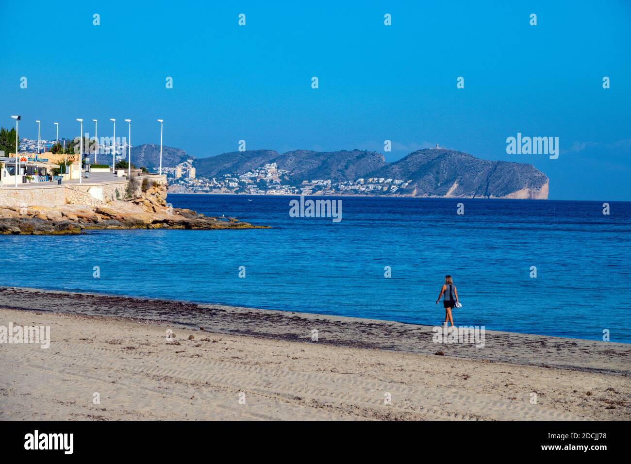 Einsame Frau am Strand an der beliebten Urlaubsdestination Calpe, an der Costa Blanca, Alicante, Spanien Stockfoto