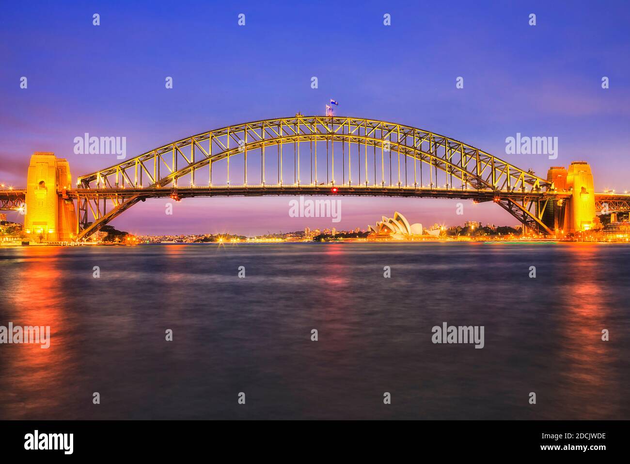 Farbenfroh beleuchtete Wahrzeichen der Stadt Sydney - die Hafenbrücke über den Hafen bei Sonnenuntergang. Stockfoto