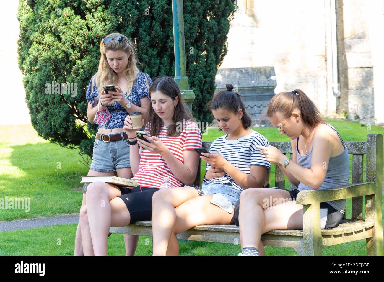 Mädchen im Teenageralter, die ihr Mobiltelefon benutzen, Market Square, Stow-on-the-Wold, Gloucestershire, England, Großbritannien Stockfoto