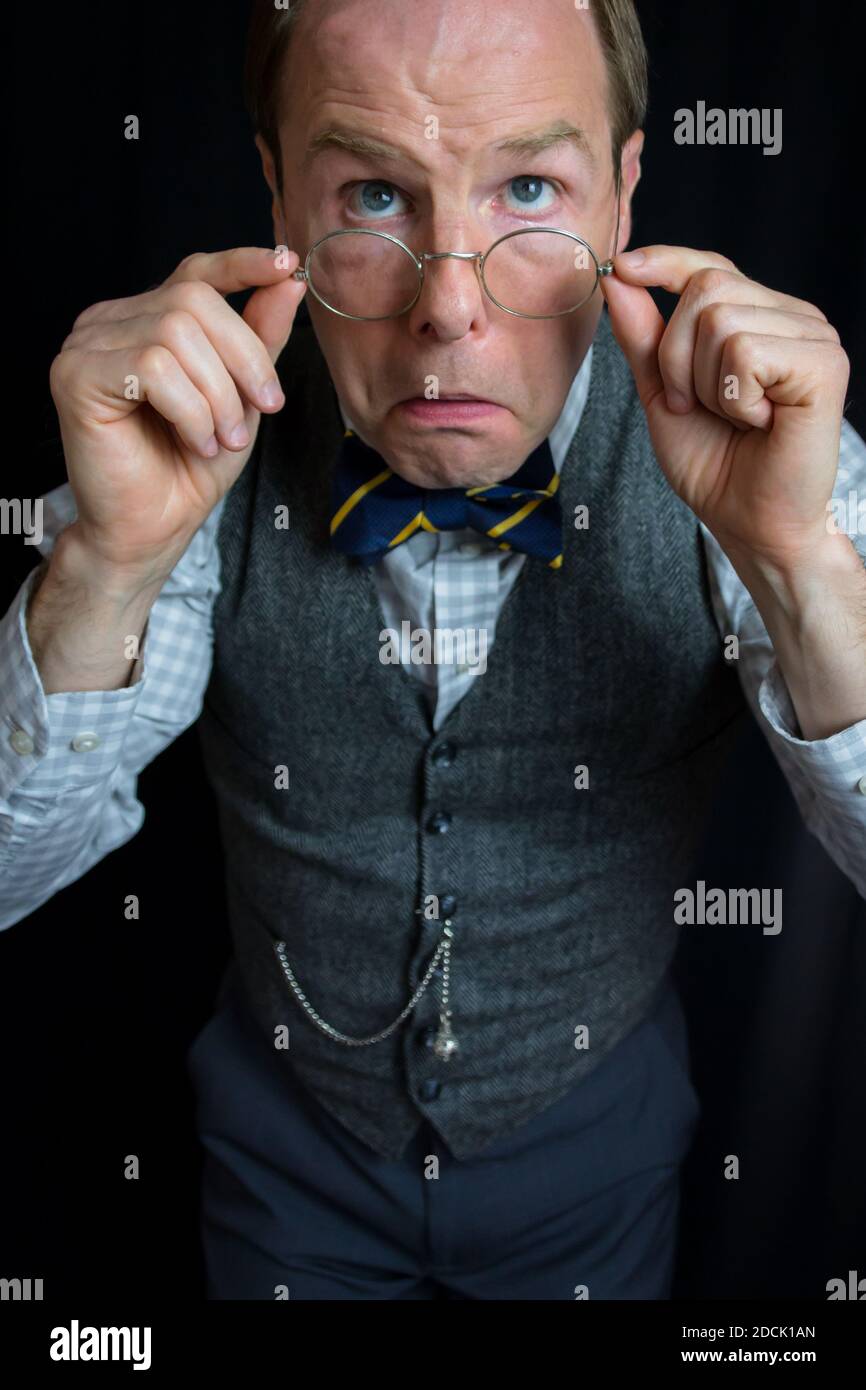 Porträt eines reifen Mannes in Tweed Weste und Fliege Anpassen Seiner Brille Stockfoto
