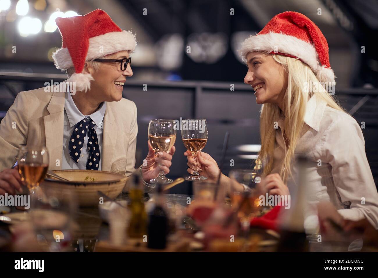 Weibliche Kollegen trinken und plaudern beim Neujahrsessen in Feiertagsstimmung in einem Restaurant. Gemeinsam, Neujahr, Feier Stockfoto