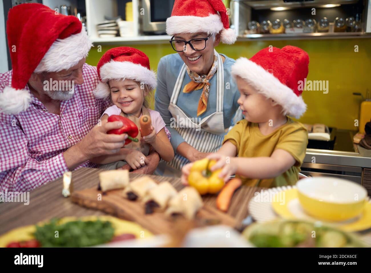 Opa, Oma und Enkel in der Küche zusammen in einer fröhlichen Atmosphäre genießen die Zubereitung von Gemüse für ein Weihnachtsessen. Weihnachten, Familie, Stockfoto