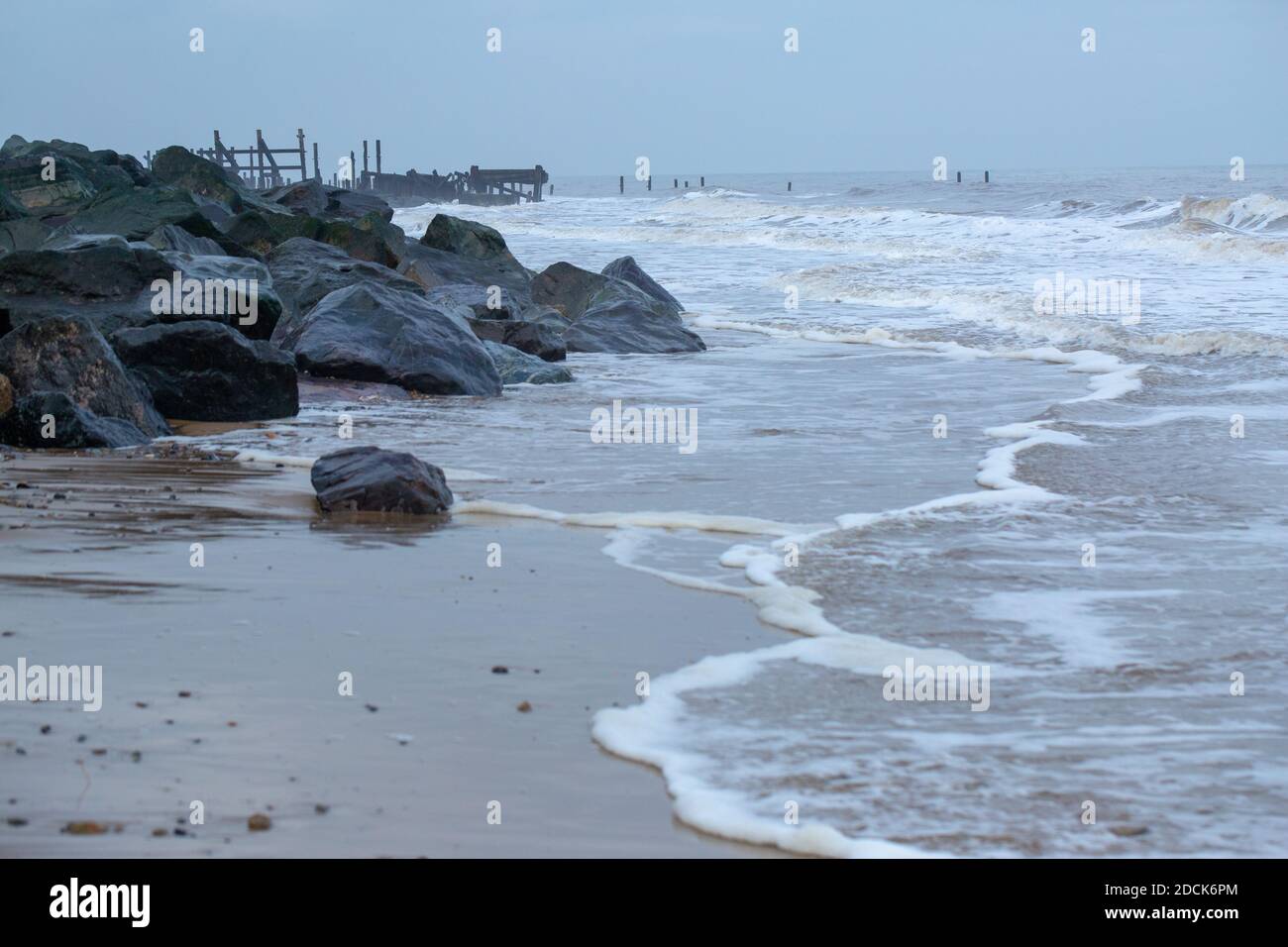 Happisburgh Beach, Norfolk. Küstenfelsen Erosion durch die Nordsee. Meeresverteidigung von importierten Norwegenfelsen links Vordergrund, Versuch, alte ti zu ersetzen Stockfoto