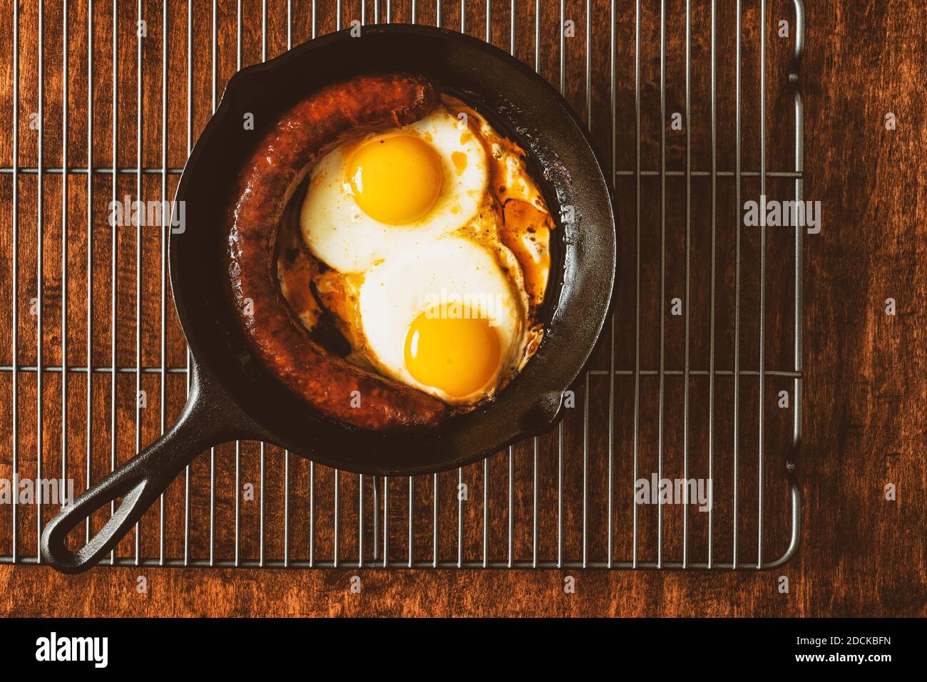 Spiegeleier mit Wurst in der Pfanne aus nächster Nähe Holzhintergrund Stockfoto