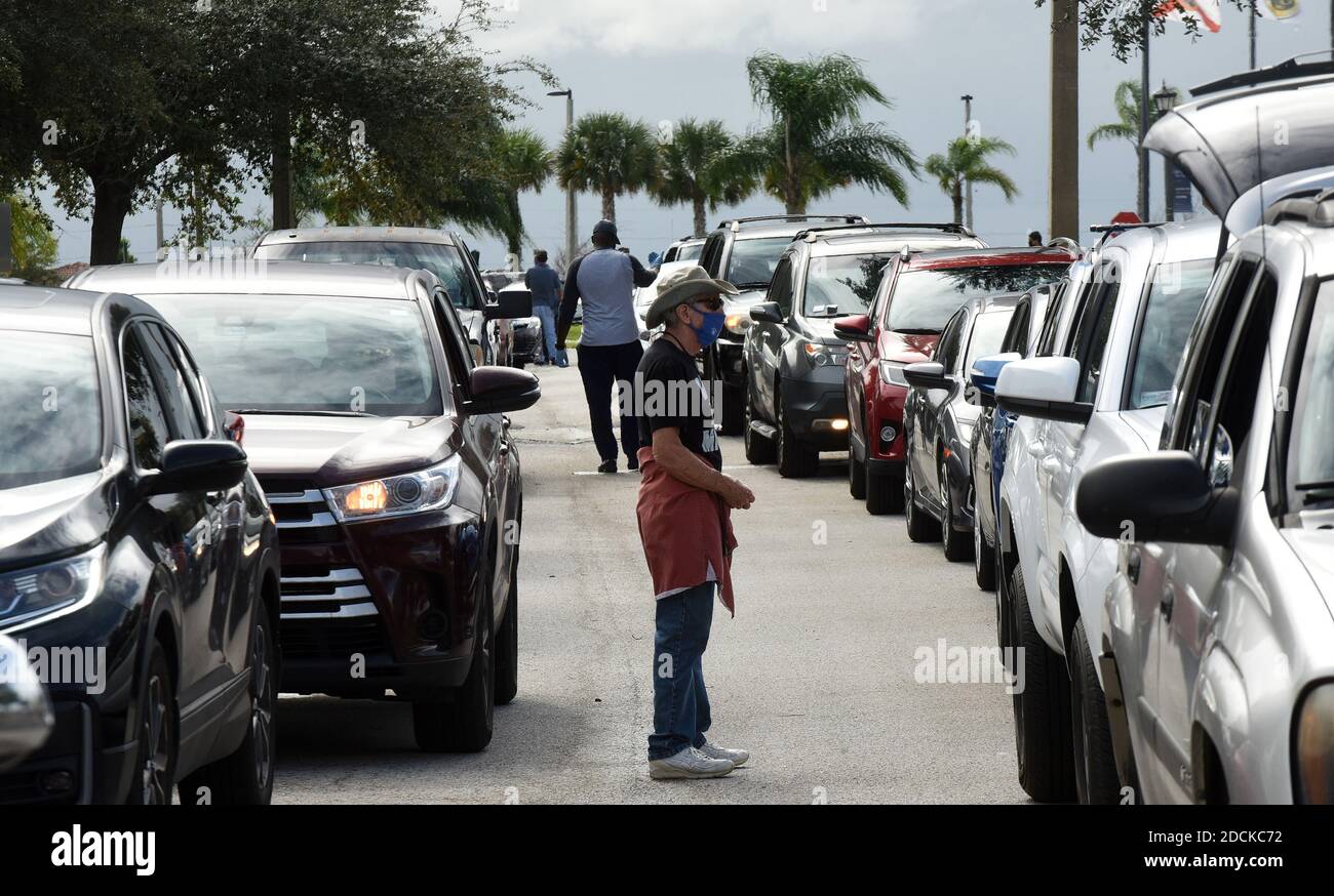 Clermont, Usa. November 2020. Freiwillige leiten den Verkehr, während die Bewohner in ihren Autos an einem Lebensmittelverteilungsplatz am Lake-Sumter State College anstehen, das von der Second Harvest Food Bank of Central Florida und lokalen Kirchen gesponsert wird.mit dem Ansatz von Thanksgiving, Tausende von Familien in der Orlando-Gegend brauchen Nahrungsmittelhilfe aufgrund von Entlassungen in der Tourismusindustrie und dem Auslaufen zusätzlicher Bundesarbeitslosengeld COVID-19. Kredit: SOPA Images Limited/Alamy Live Nachrichten Stockfoto