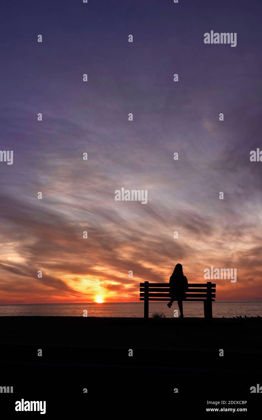 San Diego, Kalifornien, USA. November 2020. Eine Frau sitzt während des Sonnenuntergangs am Windansea Beach in La Jolla auf einer Bank. Mit COVID-19 Infektionen in ganz Kalifornien, Gov. Gavin Newsom gab eine nächtliche Ausgangssperre aus, die "unwesentliche" Aktivitäten und Versammlungen zwischen 10 Uhr und 5 Uhr Verbot.Kredit: K.C. Alfred/ZUMA Wire/Alamy Live News Stockfoto
