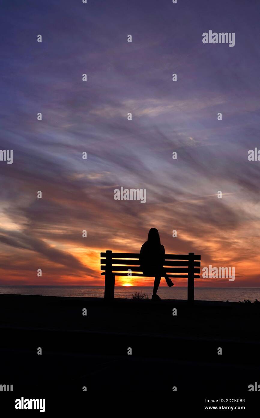 San Diego, Kalifornien, USA. November 2020. Eine Frau sitzt während des Sonnenuntergangs am Windansea Beach in La Jolla auf einer Bank. Mit COVID-19 Infektionen in ganz Kalifornien, Gov. Gavin Newsom gab eine nächtliche Ausgangssperre aus, die "unwesentliche" Aktivitäten und Versammlungen zwischen 10 Uhr und 5 Uhr Verbot.Kredit: K.C. Alfred/ZUMA Wire/Alamy Live News Stockfoto