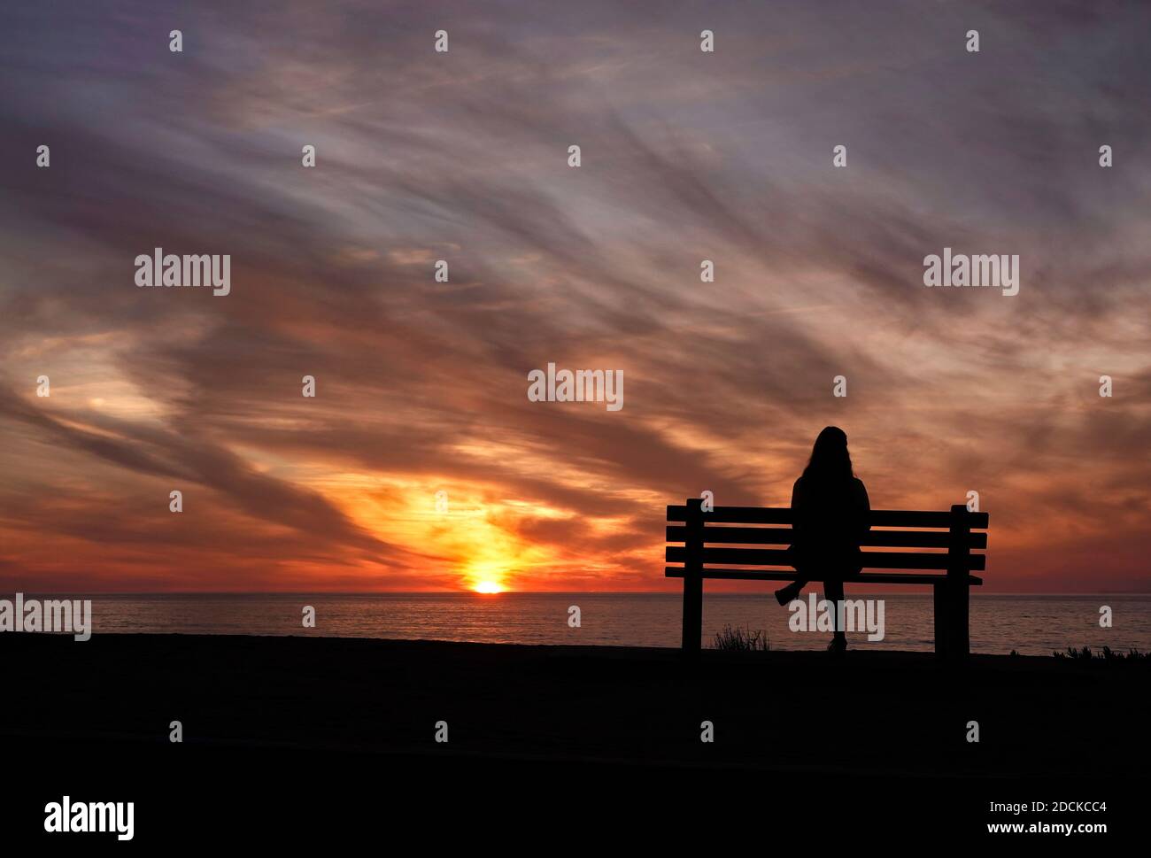 San Diego, Kalifornien, USA. November 2020. Eine Frau sitzt während des Sonnenuntergangs am Windansea Beach in La Jolla auf einer Bank. Mit COVID-19 Infektionen in ganz Kalifornien, Gov. Gavin Newsom gab eine nächtliche Ausgangssperre aus, die "unwesentliche" Aktivitäten und Versammlungen zwischen 10 Uhr und 5 Uhr Verbot.Kredit: K.C. Alfred/ZUMA Wire/Alamy Live News Stockfoto