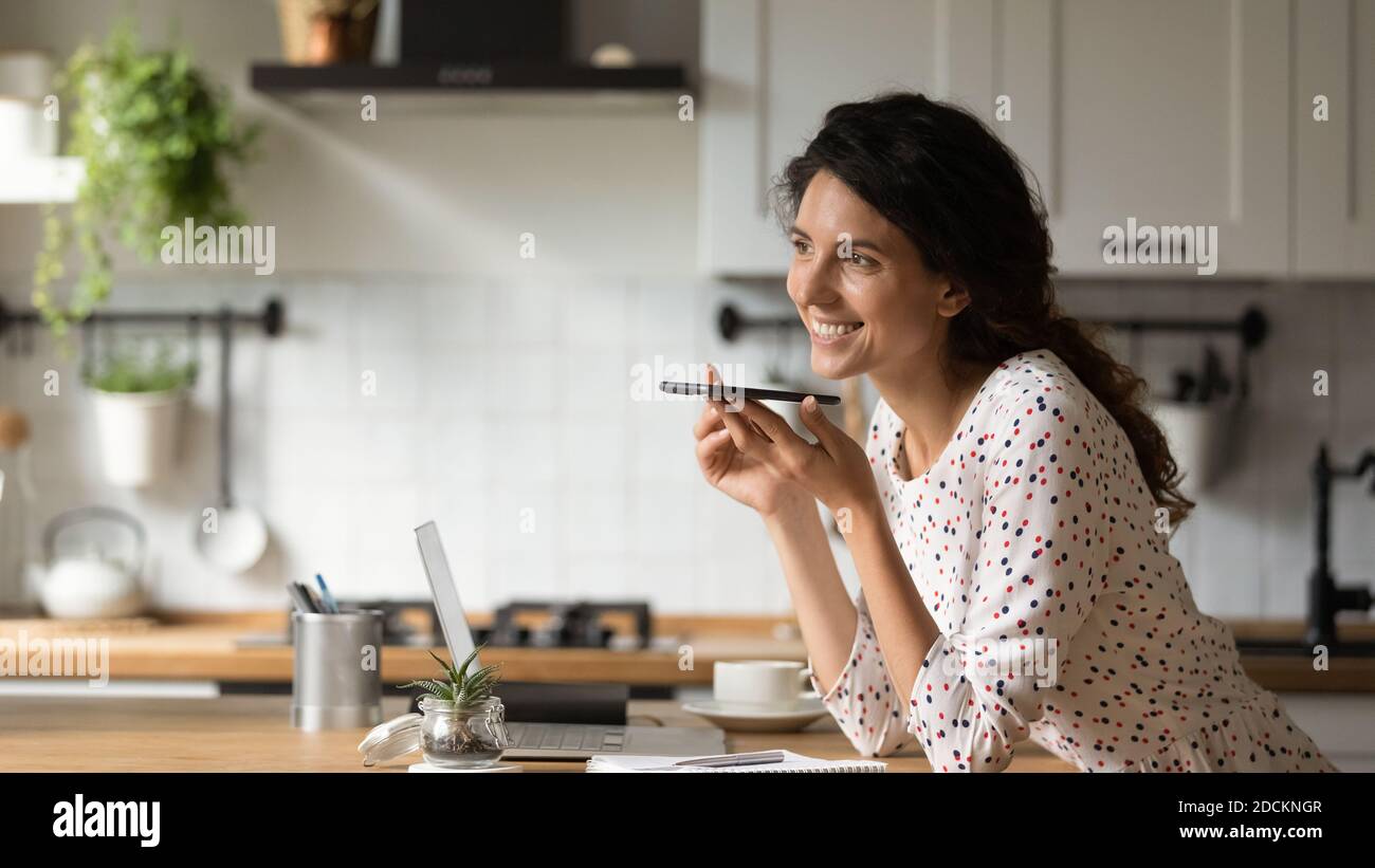 Lächelnde Frau zeichnet Sprachnachrichten auf dem Handy auf Stockfoto