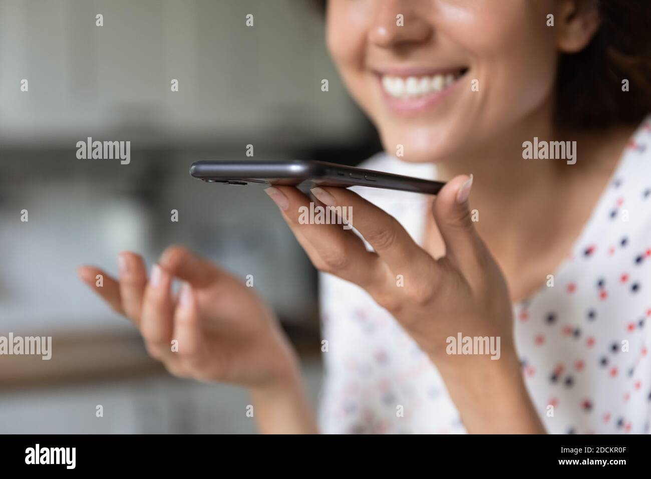 Lächelnde Frau zeichnet Sprachnachrichten auf dem Smartphone auf Stockfoto