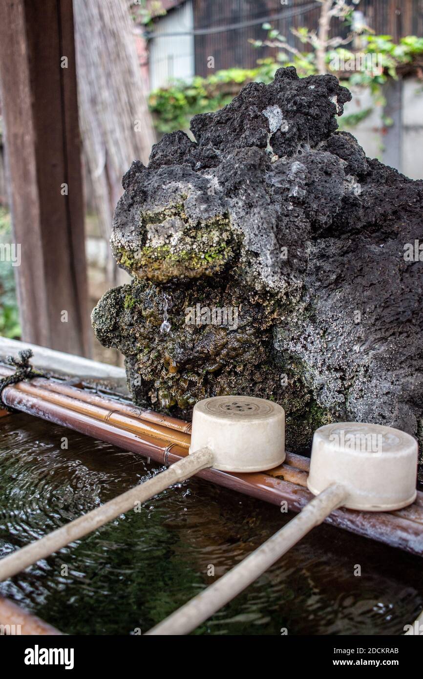 Ein natürliches steiniges Chozu Handwaschbecken bei einem Shinto Schrein in Japan Stockfoto