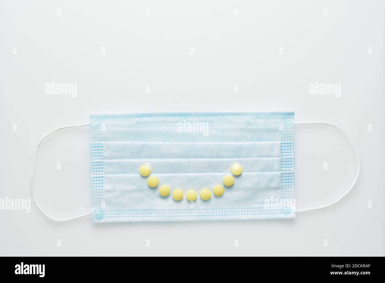 Lächeln Sie von Pillen auf Gesichtsmaske, Konzept der Körperunterstützung mit Vitaminen zur Prävention von Viren Stockfoto