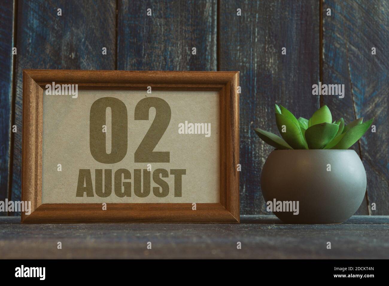 august. Tag 2 des Monats, Datum im Rahmen neben Sukkulente auf Holzhintergrund Sommermonat, Tag des Jahres Konzept. Stockfoto