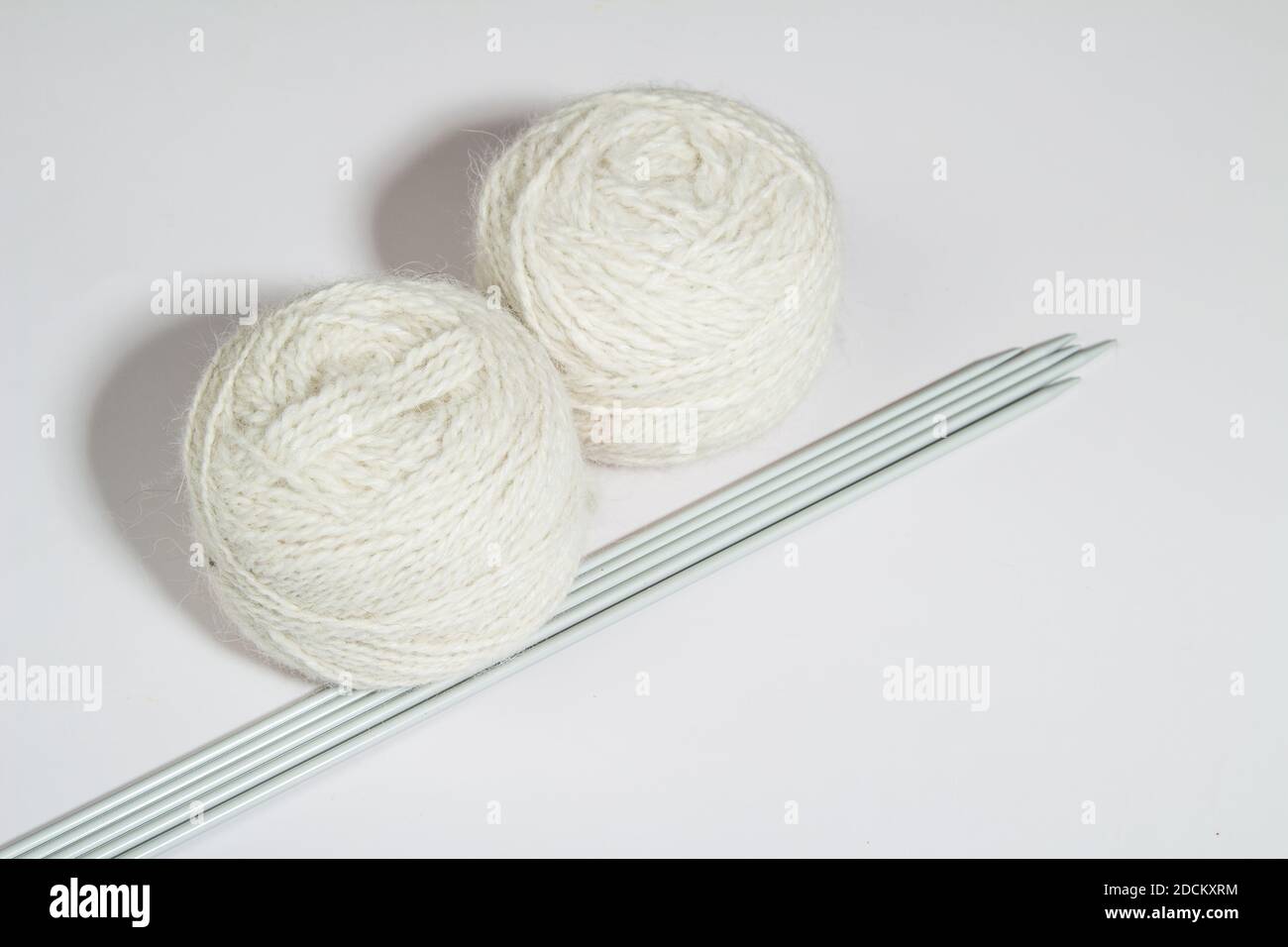 Garnkugeln zum Handstricken mit Stricknadeln auf Ein heller Hintergrund Stockfoto