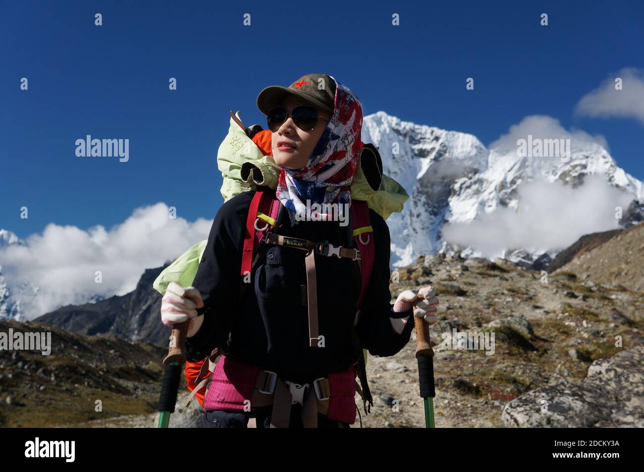 Ein Touristenmädchen von chinesischer Etnität mit Stöcken zum Wandern auf dem Hintergrund des Mount Everest während des Trekking EBC (Everest Base Camp). Stockfoto