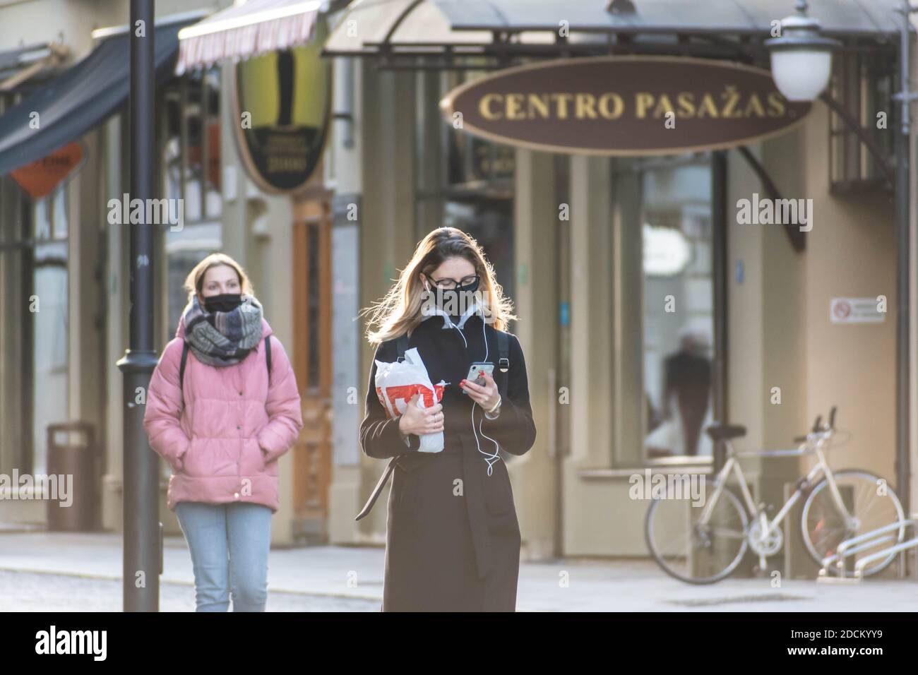 Mädchen mit Telefon trägt eine Brille und Schutzmaske zu Fuß In der Stadt in der Nähe eines Geschäfts oder Einkaufszentrum während Covid- oder Coronavirus-Ausbruch Stockfoto
