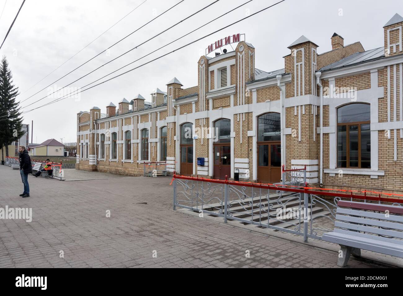 Ein Mann steht an einem bewölkten Frühlingstag auf der Bahnhofsplattform (erbaut 1913) in Ishim. Region Tjumen. Russland. Stockfoto