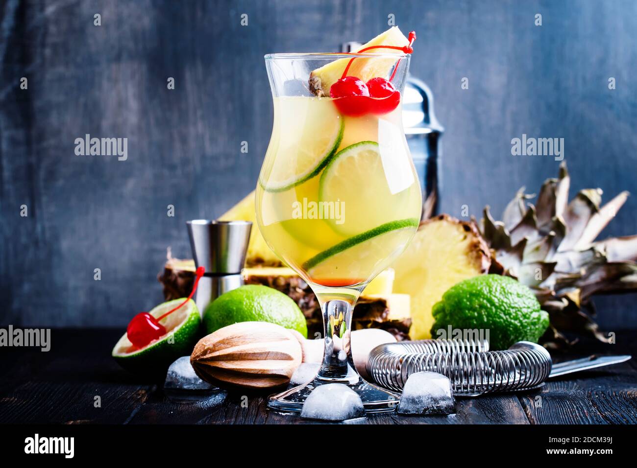 Alkoholischer Cocktail Pisco Punsch mit Schnaps, Sirup, Ananas und Limettensaft, Eis, garniert mit Limette und roter Maraschino-Kirsche, selektiver Fokus Stockfoto