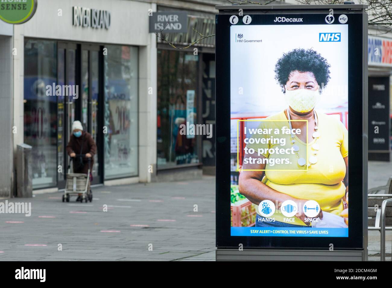 Southampton, Großbritannien, 21. November 2020. Eine OAP, die eine Maske trägt und im Stadtzentrum von Southampton spazierengeht, passiert eine digitale Werbung über das Tragen von Gesichtsbezügen, um Fremde zu schützen. Allgemeine Szenen aus dem Stadtzentrum von Southampton während der zweiten nationalen Covid-19-Sperre in England. Stockfoto