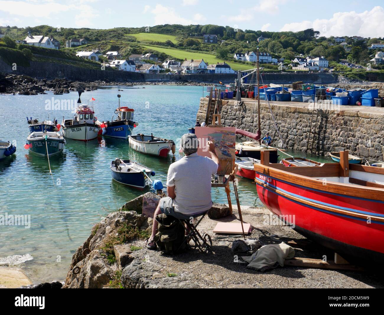 Ein Künstler bei der Arbeit am Hafen von Coverack, Cornwall. Stockfoto