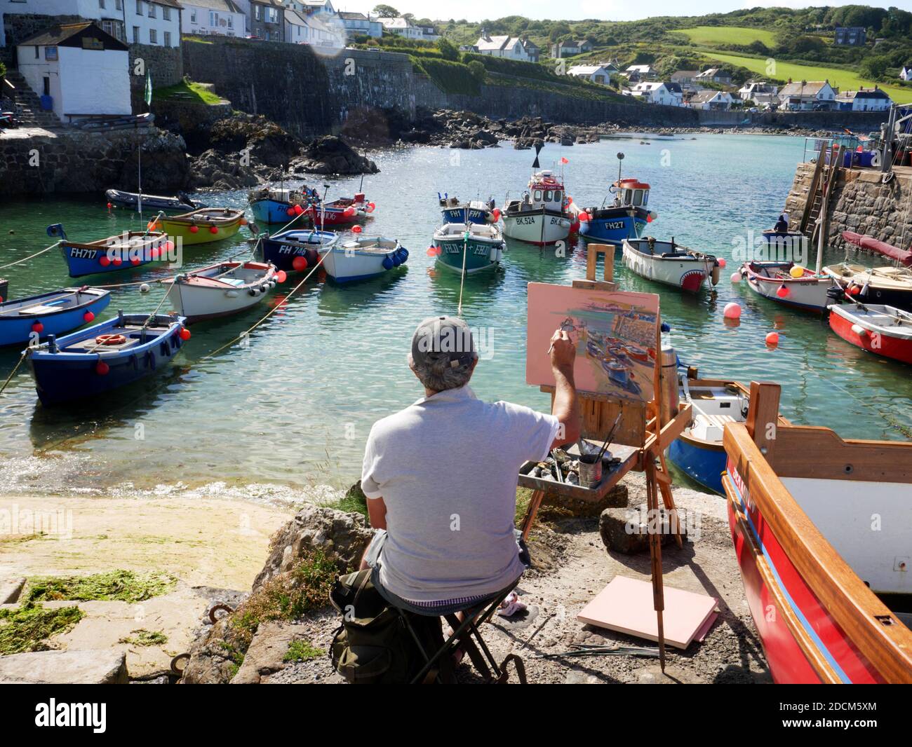 Ein Künstler bei der Arbeit am Hafen von Coverack, Cornwall. Stockfoto