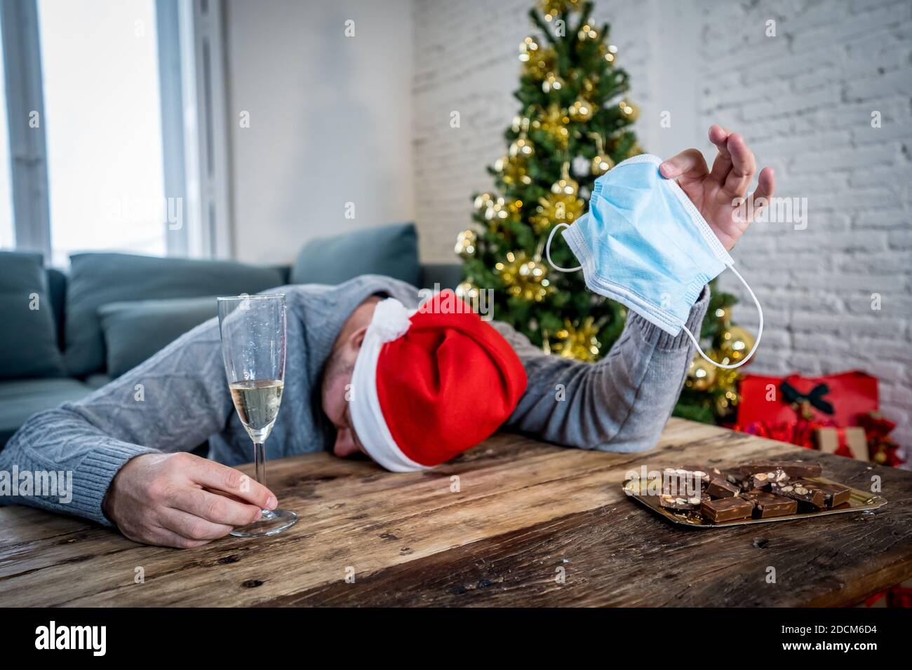 Trauriger Mann mit Maske zu Hause allein in Selbstisolation zu weihnachten Gefühl deprimiert Trauer und fehlende Familie und Freunde. COVID-19 Sperrung und Quarantäne Stockfoto