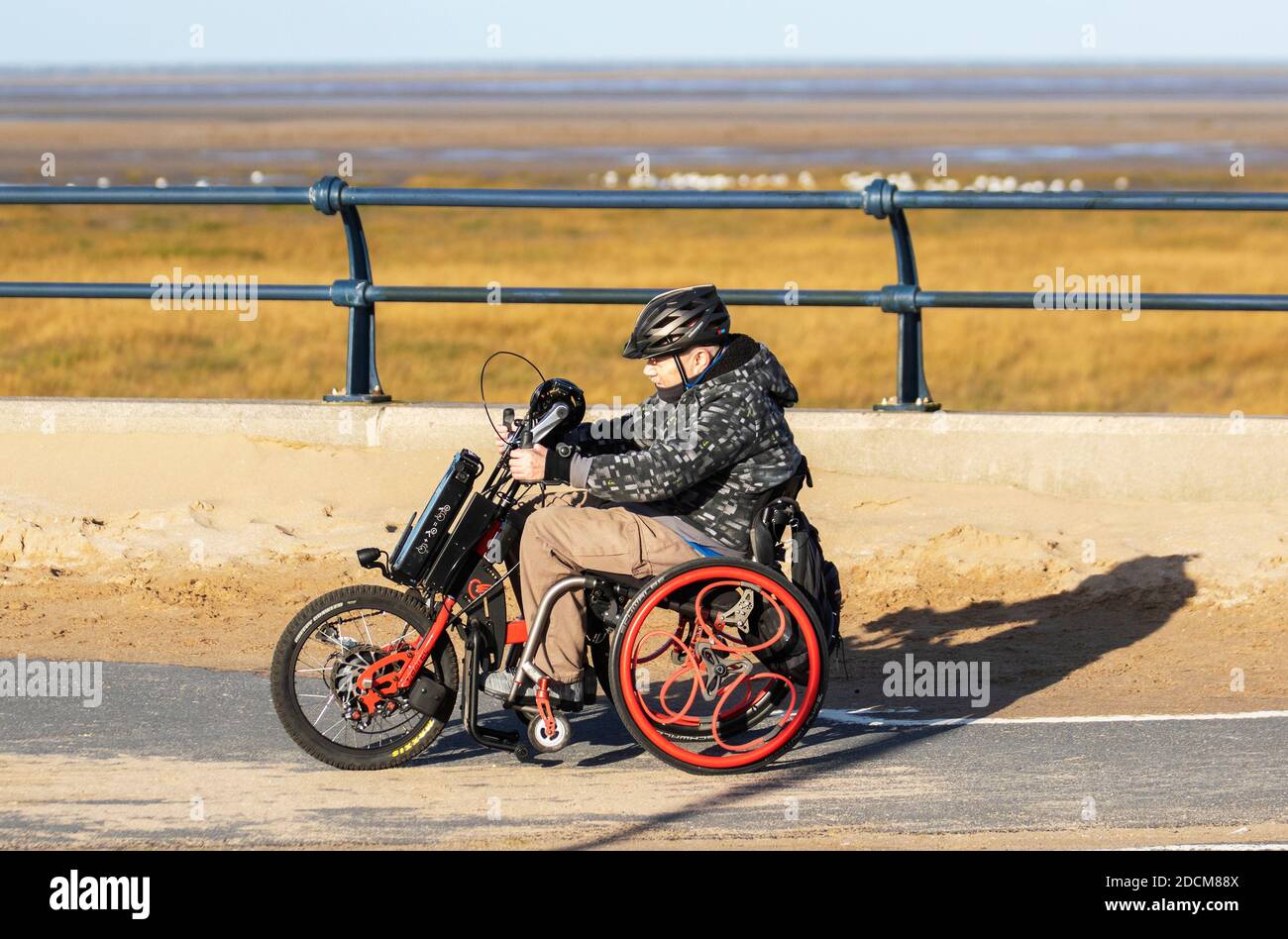 Southport, Merseyside UK Wetter. 23. November 2020 Heller sonniger kalter Tag an der Küste, als Einheimischer, der auf einem Behindertentrike reitet, die Wintersonne genießt. Kredit; MediaWorldImages/AlamyLiveNews Stockfoto