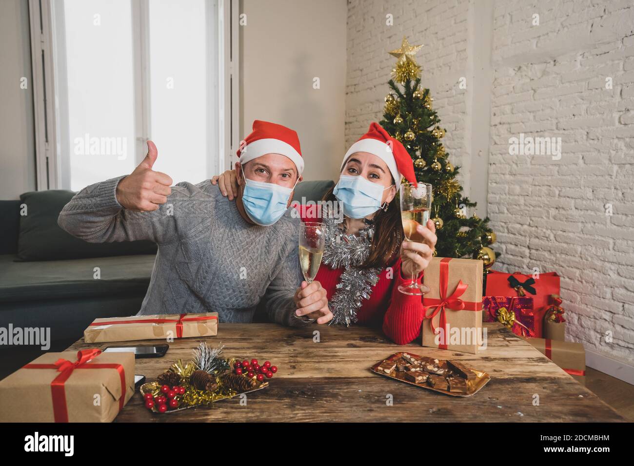 Webcam Ansicht von glücklichen Paar mit Gesichtsmaske auf Videoanruf feiern virtuelle weihnachten und Neujahr Party zu Hause im Lockdown. COVID-19 soziale Distanc Stockfoto