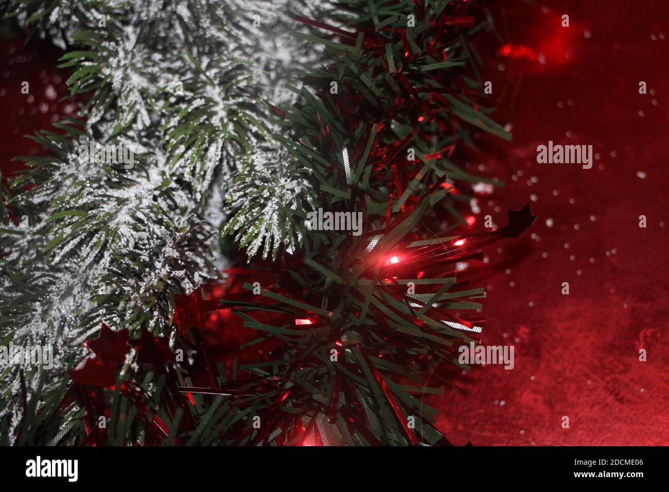 Weihnachtsschmuck auf Tannenzweigen und auf leuchtendem roten Hintergrund. Stockfoto