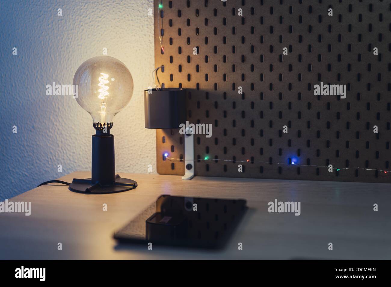 Eine Nahaufnahme einer dekorativen Glühbirne Lampe und Ein Tablet auf einem Nachttisch Stockfoto