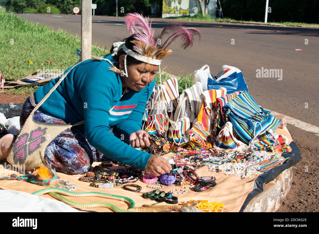 Eine Frau, die der Gruppe der guaranischen indigenen Völker angehört und ihre handgefertigten Kunsthandwerke neben einer Hauptstraße an Touristen verkauft, Stockfoto