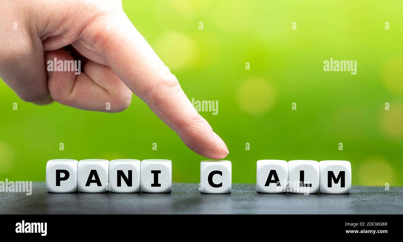 Hand bewegt Würfel und ändert das Wort Panik zu Ruhe. Stockfoto