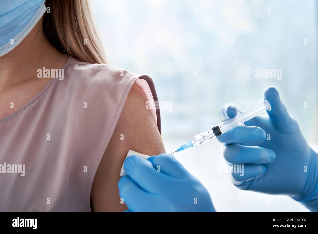 Männlicher Arzt macht covid 19 Impfinjektion in der Schulter der weiblichen Patienten. Stockfoto