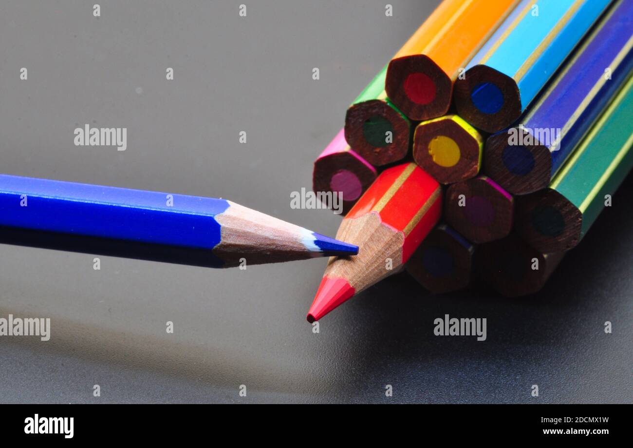 Metapher für Strategie und Teamwork, dargestellt durch Farbstifte auf schwarzem Hintergrund, die das Konzept des Denkens außerhalb des Tisches darstellen. Stockfoto