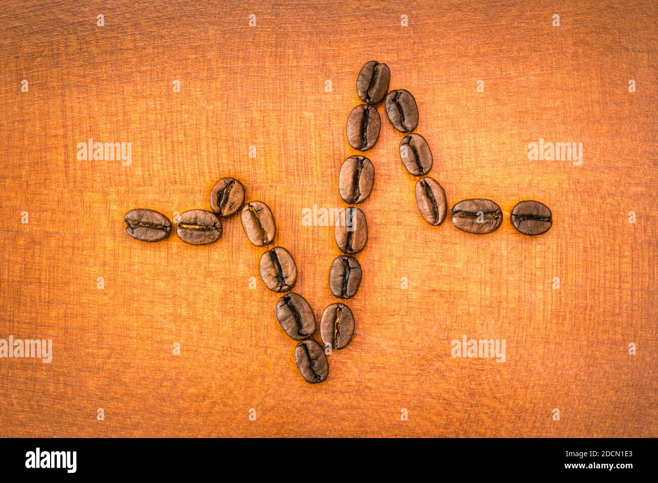 Geröstete Kaffeebohnen bilden eine Herzschlag Lebensader auf Holz symbolisieren Vitalität und Energie im Leben Stockfoto