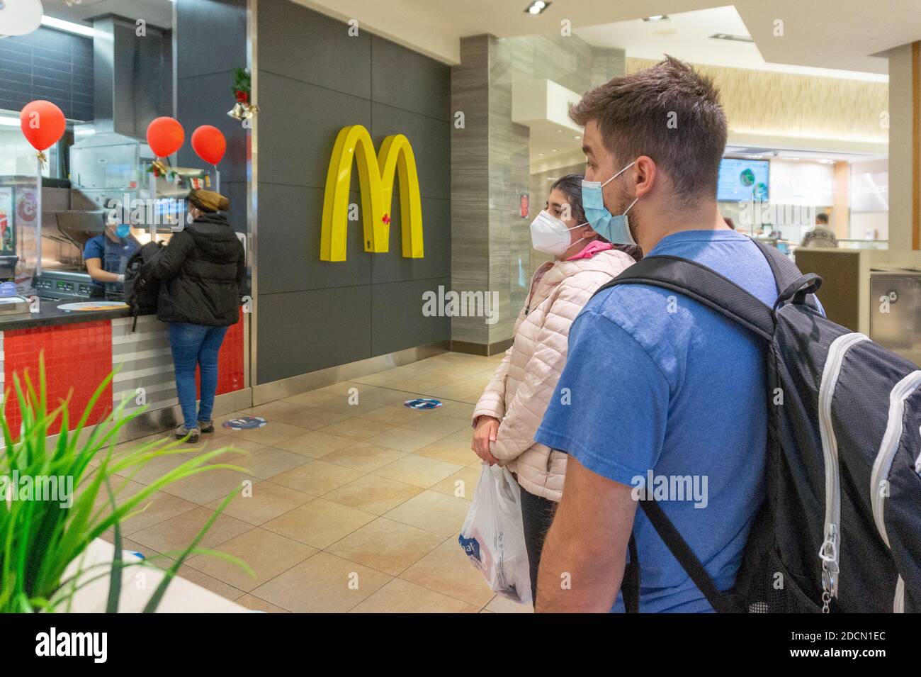 Junge Menschen warten während der Covid-19-Pandemie in einem McDonald's in der Schlange. Stockfoto