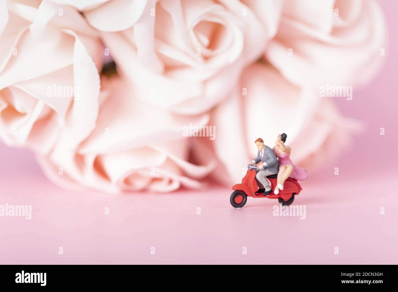 Nahaufnahme eines Paares auf Moped-Figuren auf Pink Backfrund Stockfoto