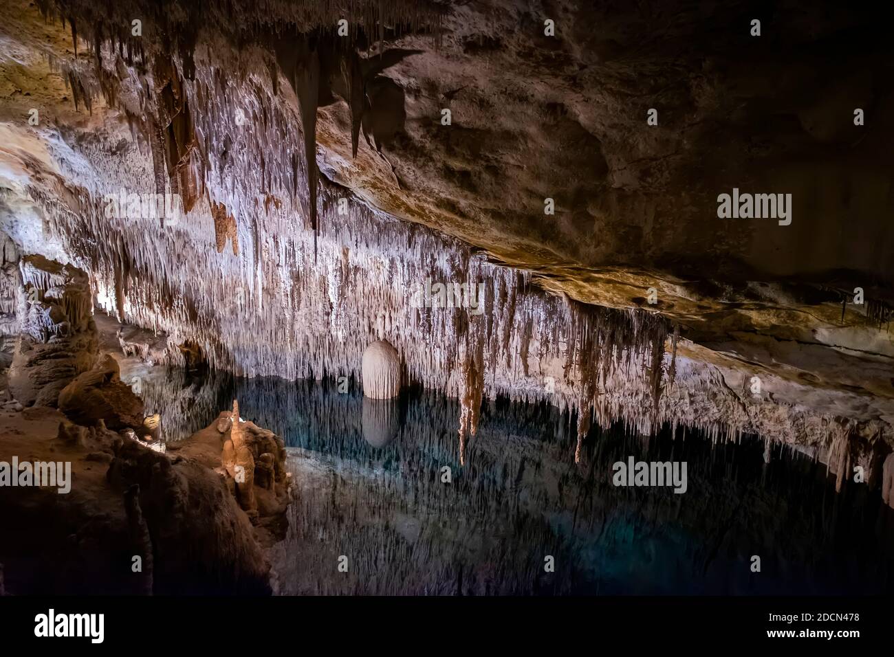 Stalagmiten und Stalaktiten und ein unterirdischer See in den Drachhöhlen in Palma de Mallorca, Balearen, Spanien, horizontal Stockfoto