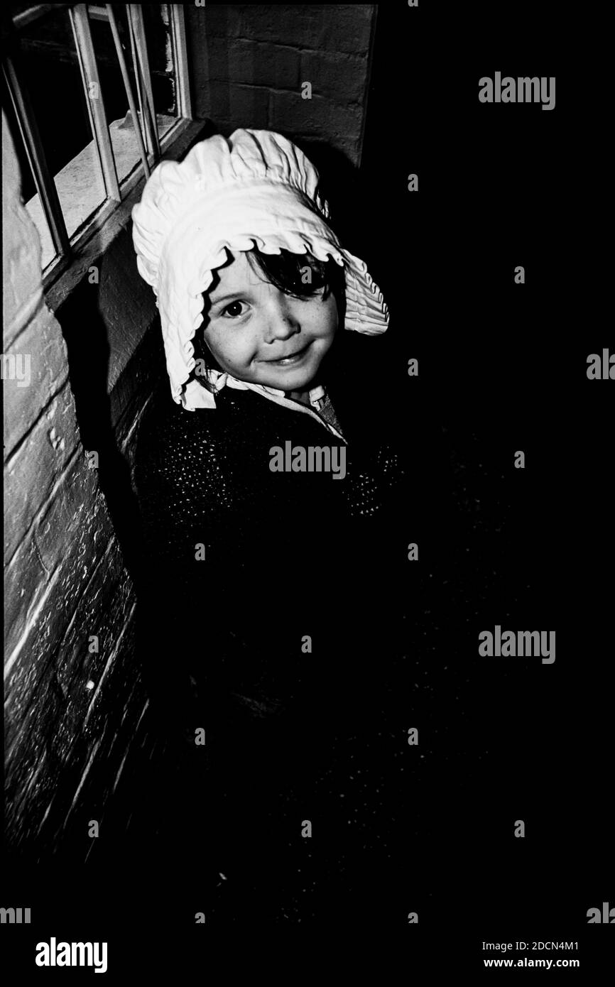 Ein Schwarz-Weiß-Foto eines jungen Mädchens / Kindes in der Kleidung eines Paupers aus dem 19. Jahrhundert in einem Arbeitshaus Stockfoto