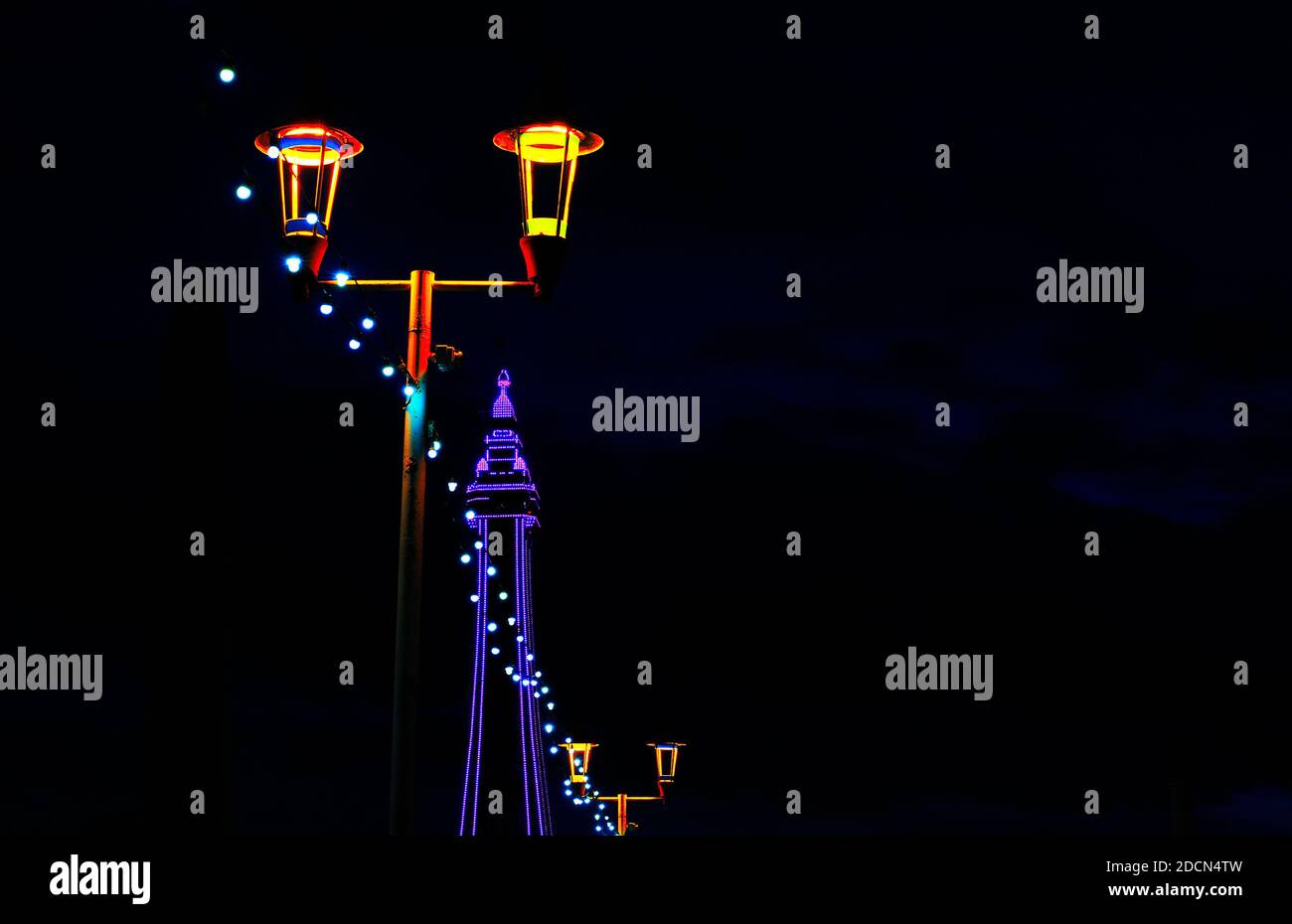 Eine Reihe von Glühbirnen verbindet Lampenpfosten und beleuchteten Blackpool Turm im Hintergrund Stockfoto