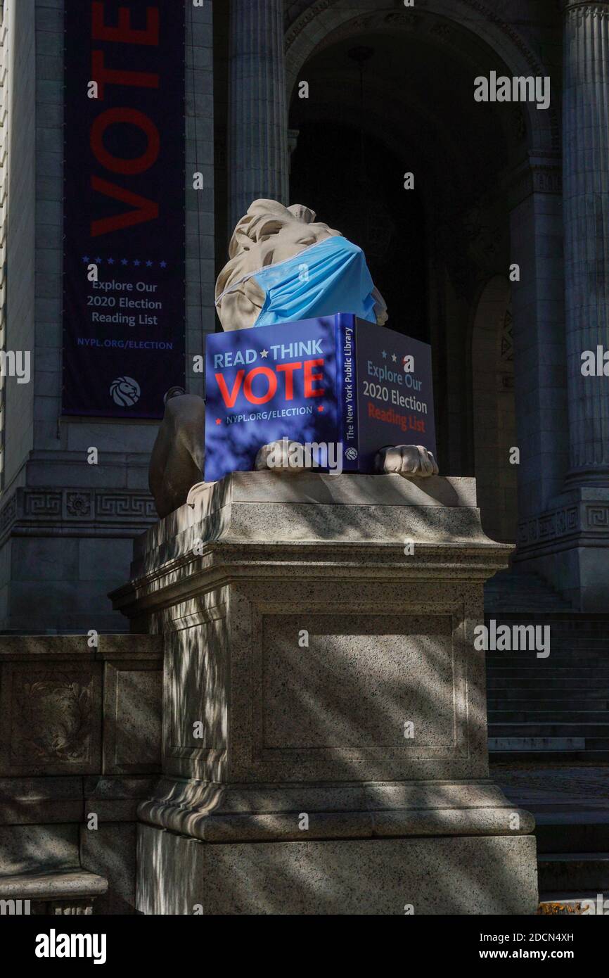 Löwe vor der New York Public Library trägt Maske und hält ein Buch "lesen, denken Abstimmung" Stockfoto