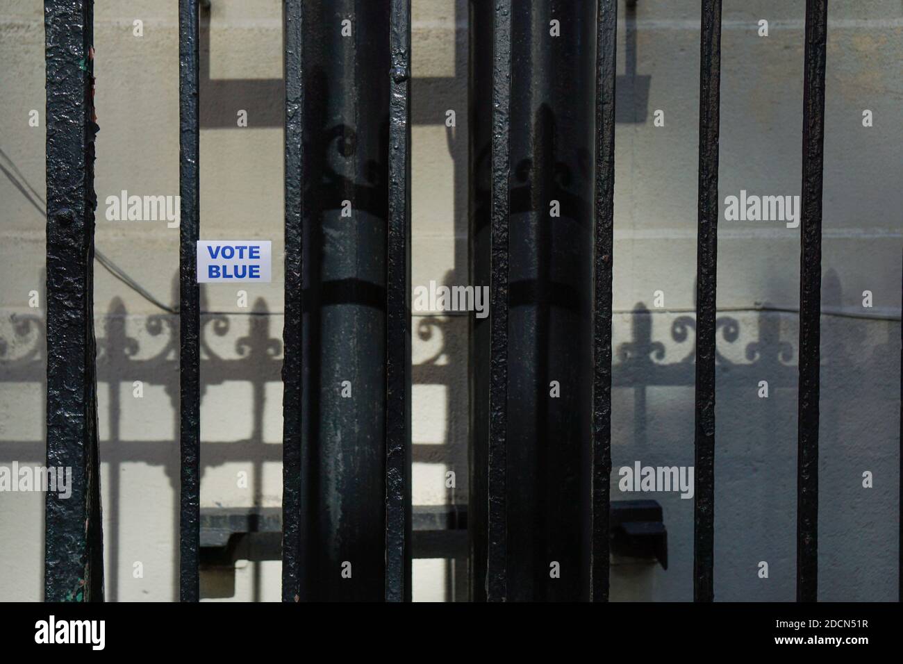 NEW YORK - 17. Oktober 2020: 'Vote Blue' Aufkleber an der Wand durch ein Tor geschossen. Stockfoto