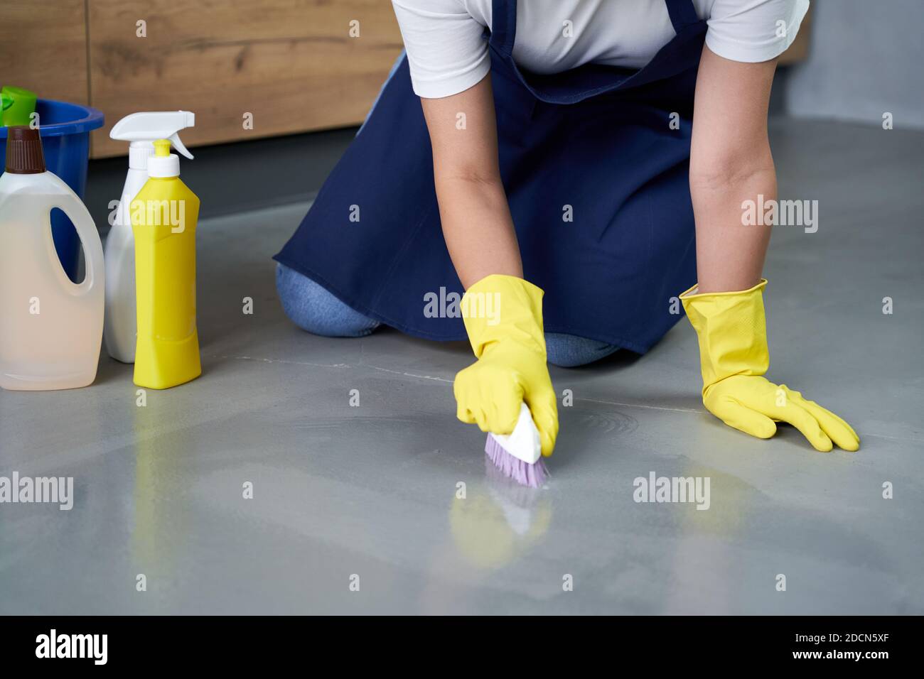 Glänzende Oberfläche. Nahaufnahme der Hände der jungen Frau in gelben Handschuhen Reinigung Boden mit Waschmitteln zu Hause. Hausarbeit und Housekeeping, Reinigungsdienstkonzept Stockfoto