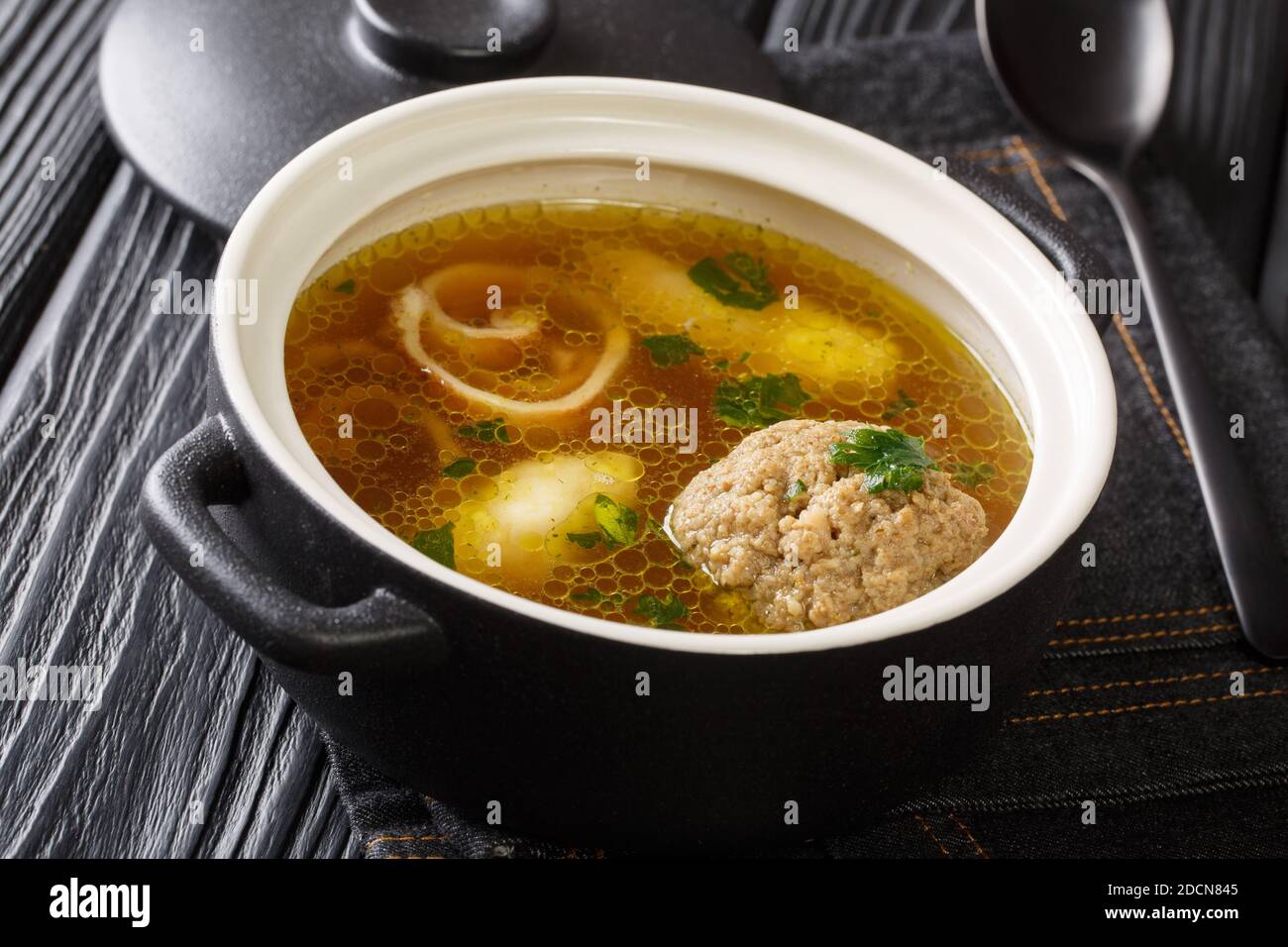Köstliche Wiener Rindsuppe auf der Basis von Rinderbrühe mit Knödeln aus der Nähe in einem Topf auf dem Tisch. Horizontal Stockfoto