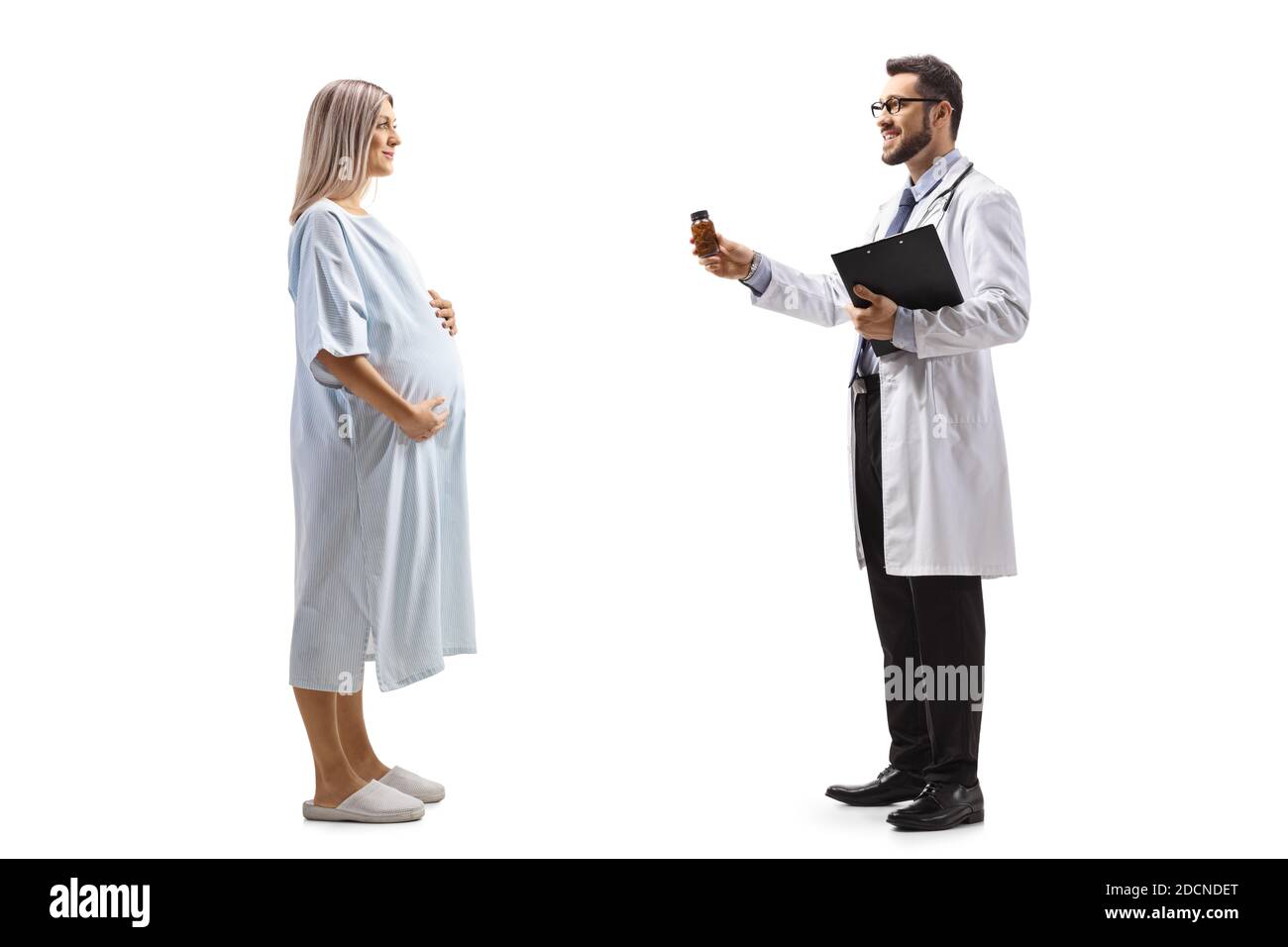 In voller Länge Profil Aufnahme eines männlichen Arzt geben ein Vitamintabletten für eine schwangere Patientin in einem Krankenhaus Kleid isoliert auf weißem Hintergrund Stockfoto